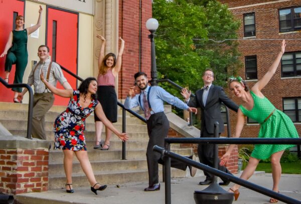Dancers pose in differing fun swing dancing positions on the steps outside of McGowan Hall